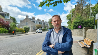 Douglas Lumsden standing beside a road in Aberdeen.